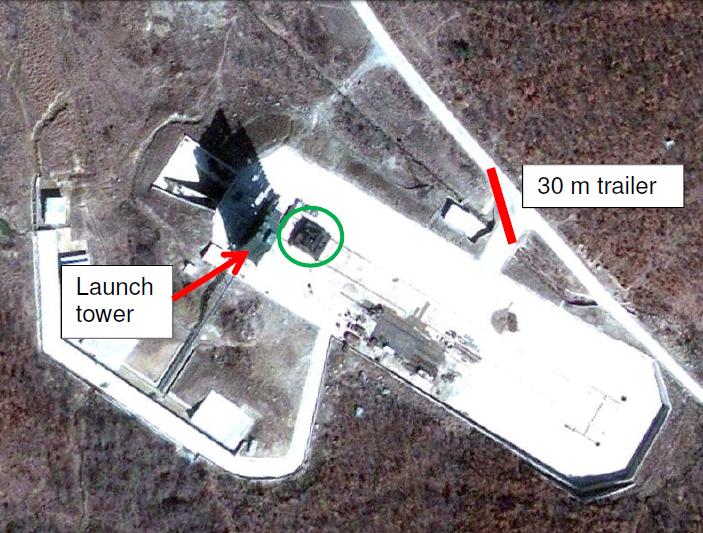 Figure 3: This picture shows the movable launch pad (in the green circle) on parallel tracks that run across the launch area. The tower is the dark rectangle to left of the green circle; it is casting a long shadow to the northwest. The red line shows the size of a 30-meter trailer. (Image from Google Earth, March 25, 2009)